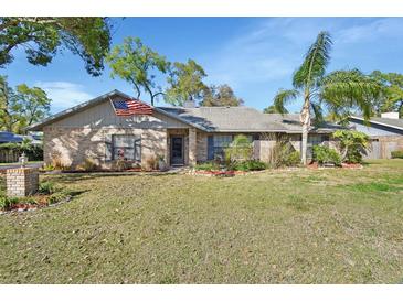 Charming single-story brick home featuring a well-manicured lawn, front flower beds and an American flag at 725 Briarcrest Dr, Orange City, FL 32763