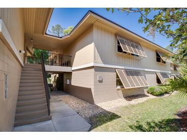 Two-story condo building with stairs, shuttered windows, and well-maintained landscaping at 120 Hibiscus Woods Ct # 14D, Deltona, FL 32725