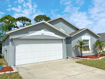 This beautiful home features a two car garage, well manicured lawn, and front entrance with vibrant landscaping at 209 Oak Branch Drive, Edgewater, FL 32141