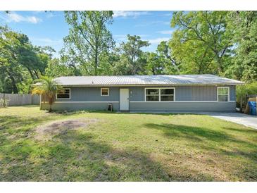 Charming single-story home featuring a metal roof, well-maintained lawn, and mature trees at 321 Wade Ave, Deland, FL 32724