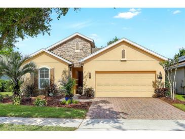 Inviting single-story home with a well-manicured lawn, stone accents, and a two-car garage at 1386 Hazeldene Mnr, Deland, FL 32724