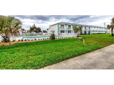 Charming condo building featuring a refreshing community pool with a well-maintained green lawn at 2480 Ocean Shore Blvd # 120, Ormond Beach, FL 32176