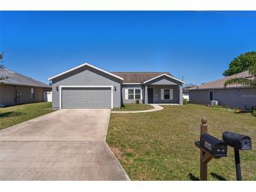 Charming single-Gathering home featuring a well-manicured lawn, a two-car garage, and a classic gray exterior at 303 Puffer Ct, Kissimmee, FL 34759