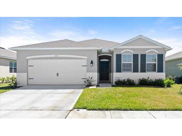 Charming single-story home with a two-car garage, gray exterior and well-maintained front lawn at 322 E Merimont Ln, Ormond Beach, FL 32174