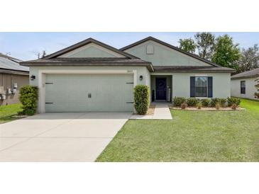 This home features a two car garage, a manicured lawn and landscaping at 3845 Arborvitae Way, Deland, FL 32724