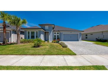 Charming single-story home featuring a well-manicured lawn, palm tree, and paver driveway, presenting excellent curb appeal at 418 Aquamarine Way, Daytona Beach, FL 32124