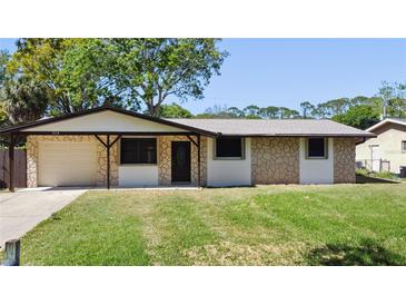 Charming single-story home featuring stone accents, a covered porch, and a well-manicured lawn at 614 Johnson Dr, Ormond Beach, FL 32174