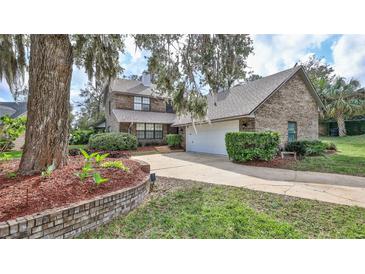 Charming two-story brick home with a well-manicured lawn, lush landscaping and mature trees at 1 Fox Hollow Dr, Ormond Beach, FL 32174