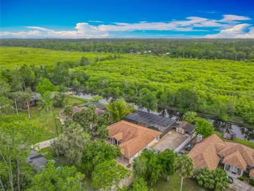 Beautiful aerial view of a single-Gathering home with a screened pool, lush landscaping, and amazing waterfront views at 1578 Stone Trl, Deltona, FL 32725