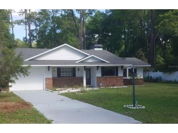 Charming single-story home featuring a brick accent wall and a well-manicured lawn at 26225 Troon Ave, Mount Plymouth, FL 32776