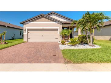 Charming single-story home featuring a brick driveway, two-car garage, and tropical landscaping at 3128 Crab Trap Dr, New Smyrna Beach, FL 32168
