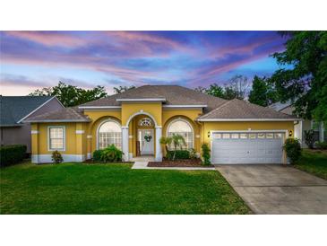 Charming, yellow single-story home featuring arched windows, a well-maintained lawn, and a two-car garage at 316 Oak Springs Dr, Debary, FL 32713