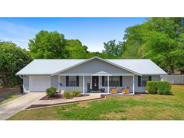 Charming single-story home with a new silver metal roof, inviting front porch, manicured lawn and mature landscaping at 4836 Ne 26Th Ter, Ocala, FL 34479