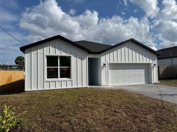 Charming single-story home with a white exterior, dark roof, two-car garage, and well-manicured lawn at 810 W 24Th St, Sanford, FL 32771