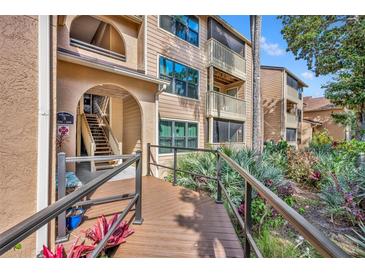 Inviting condo building featuring a wooden walkway and lush tropical landscaping at 1401 S Palmetto Ave # 300, Daytona Beach, FL 32114