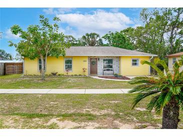 Charming yellow home featuring a well-manicured lawn and welcoming front entrance with bench and plants at 1511 Jack St, Tavares, FL 32778