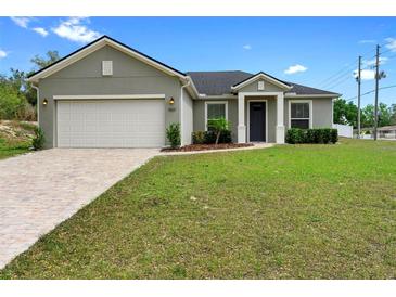 Charming single-story home featuring a well-maintained lawn, a two-car garage, and manicured landscaping at 1601 Toledo Ave, Deltona, FL 32725