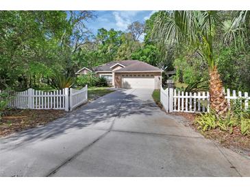 Charming single-story brick home with a well-manicured lawn and a white picket fence lined driveway at 1925 Hamilton Ave, Orange City, FL 32763