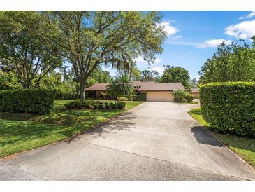 Charming home with a large front yard, mature trees, lush landscaping, and a long driveway leading to a two-car garage at 229 Riverbend Rd, Ormond Beach, FL 32174