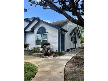 Charming single-story home with white siding, blue trim, and beautifully landscaped front yard at 2596 Lancaster Ct, Apopka, FL 32703