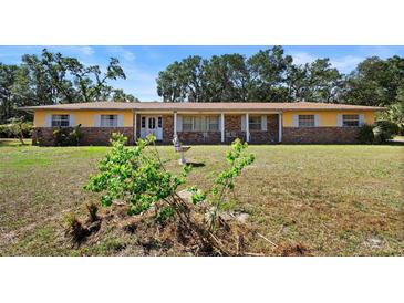 Ranch style home featuring a combination of brick and yellow siding, covered porch, and a large front yard at 2919 Griffin Rd, Leesburg, FL 34748