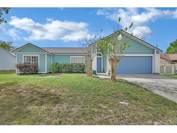 Charming, single-story home featuring a well-manicured lawn, complemented by a colorful exterior and an attached garage at 2937 Garret St, Deltona, FL 32738