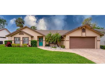 Charming single-story home with a well-manicured lawn, a vibrant turquoise door, and beautiful landscaping at 4029 N Waterbridge Cir, Port Orange, FL 32129