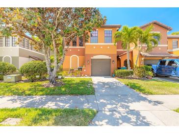 Two-story townhome featuring well-kept landscaping, a two-car garage, and an inviting orange and brown color scheme at 6078 Tivoli Gardens Blvd, Orlando, FL 32829