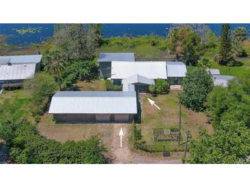 Stunning aerial view of a lakeside property with a detached garage and lush landscaping at 160 Rose Ave, Lake Helen, FL 32744