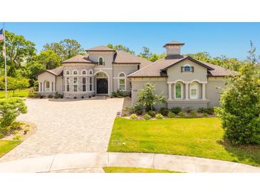 Elegant home featuring manicured lawn, brick driveway, turret entrance, and stone accents at 1855 Cattle Creek Ln, Port Orange, FL 32128