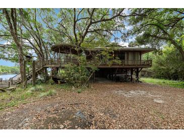 Unique home exterior featuring elevated deck and a covered area underneath, surrounded by lush trees at 4293 Cypress Bnd, Geneva, FL 32732