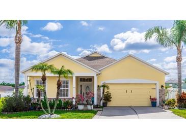 Charming, one-story, yellow home with a well-manicured lawn, palm trees, and an attached two-car garage at 112 Coral Reef Ct, Sanford, FL 32771