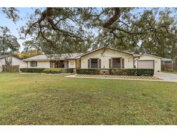 Charming single-story home featuring a manicured lawn, mature trees, and charming curb appeal at 1128 Heidi Ct, Deland, FL 32720