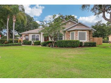 Charming single-story home with lush landscaping and a manicured lawn under a bright blue, partially cloudy sky at 1504 Ginger Snap, Deland, FL 32720