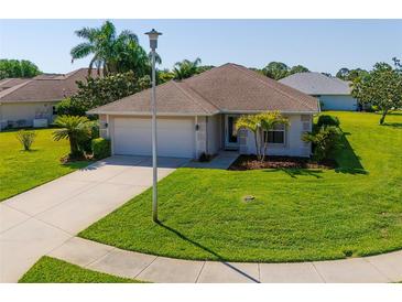 Charming single-story home with a well-manicured lawn, tropical landscaping, and a paved driveway at 1860 Turnbull Lakes Dr, New Smyrna Beach, FL 32168