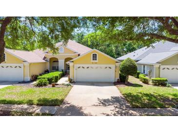 Charming yellow single-story home with a two-car garage, mature landscaping, and a well-manicured lawn at 3140 Kailani Ct, Ormond Beach, FL 32174