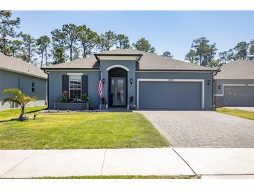 Charming single-story home featuring a well-manicured lawn, brick driveway, and an attached two-car garage at 6006 Mount Zion Cir, Deland, FL 32724