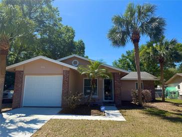 Charming single-story home featuring a manicured lawn, palm trees, and an attached one-car garage at 670 W Tall Pine Ter, Deland, FL 32724