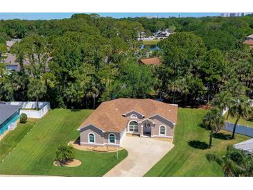 Landscaped front yard of a single-story home with a driveway leading to the attached garage at 823 Wooddusk Dr, Port Orange, FL 32127
