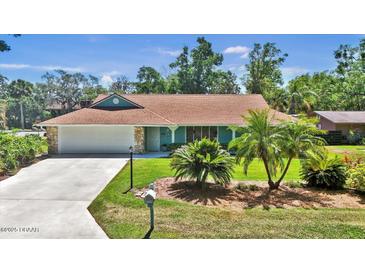 Charming ranch-style home featuring a well-manicured lawn and mature palm trees at 1 Cobblestone Trl, Ormond Beach, FL 32174