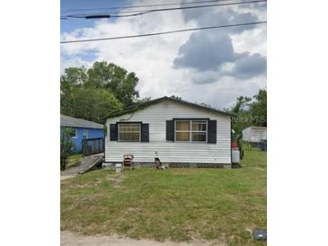 Exterior of a one-story house with white siding and black shutters surrounded by a grassy lawn at 1228 S Parsons Ave, Deland, FL 32720