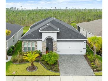 Charming single-story home featuring a manicured front yard and an attached two-car garage with an attractive paved driveway at 225 Mosaic Blvd, Daytona Beach, FL 32124