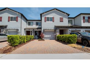Townhome with brick driveway, attached garage, manicured shrubs, and neutral paint at 258 Rustic Loop, Sanford, FL 32771