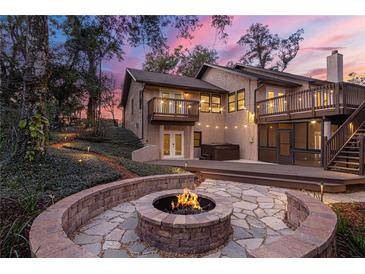 Inviting backyard featuring a fire pit and an elevated deck with string lights and hot tub at 2628 Spruce Creek Blvd, Port Orange, FL 32128