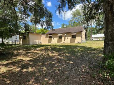 View of the home from the expansive backyard, surrounded by trees at 326 South St, De Leon Springs, FL 32130
