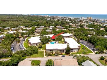 Aerial view of condo complex featuring a sparkling community pool and lush landscaping at 3800 Saxon Dr # 150, New Smyrna Beach, FL 32169