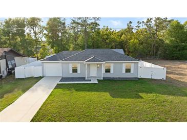 Charming one-story home with a well-manicured lawn, white picket fence, and a single-car garage for convenient parking at 430 Spring Dr, Ocala, FL 34472