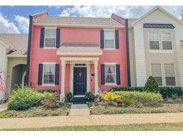 Charming two-story townhome featuring a bright pink facade, black shutters, and manicured landscaping at 103 Manor View Ln, Deland, FL 32724