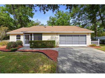 Charming home featuring a manicured front yard, a screened entry, and a two-car garage at 1057 Shady Hollow Dr, Deland, FL 32724