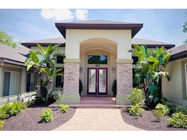 Elegant home entrance featuring a double door, stone pillars and brick walkway lined with tropical plants and lush landscaping at 183 Mcgregor Rd, Deland, FL 32720
